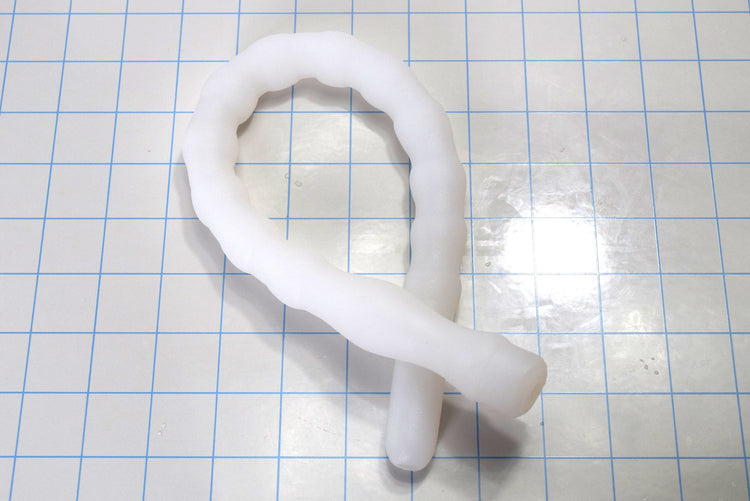 Coiled translucent white Shower Shooter 18-inch silicone enema nozzle on measurement grid displaying extreme flexibility.