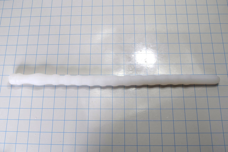 Shower Shooter 18-inch silicone enema nozzle laid flat on grid paper showing 12 expansion ribs, smooth entry tip, and retention neck.