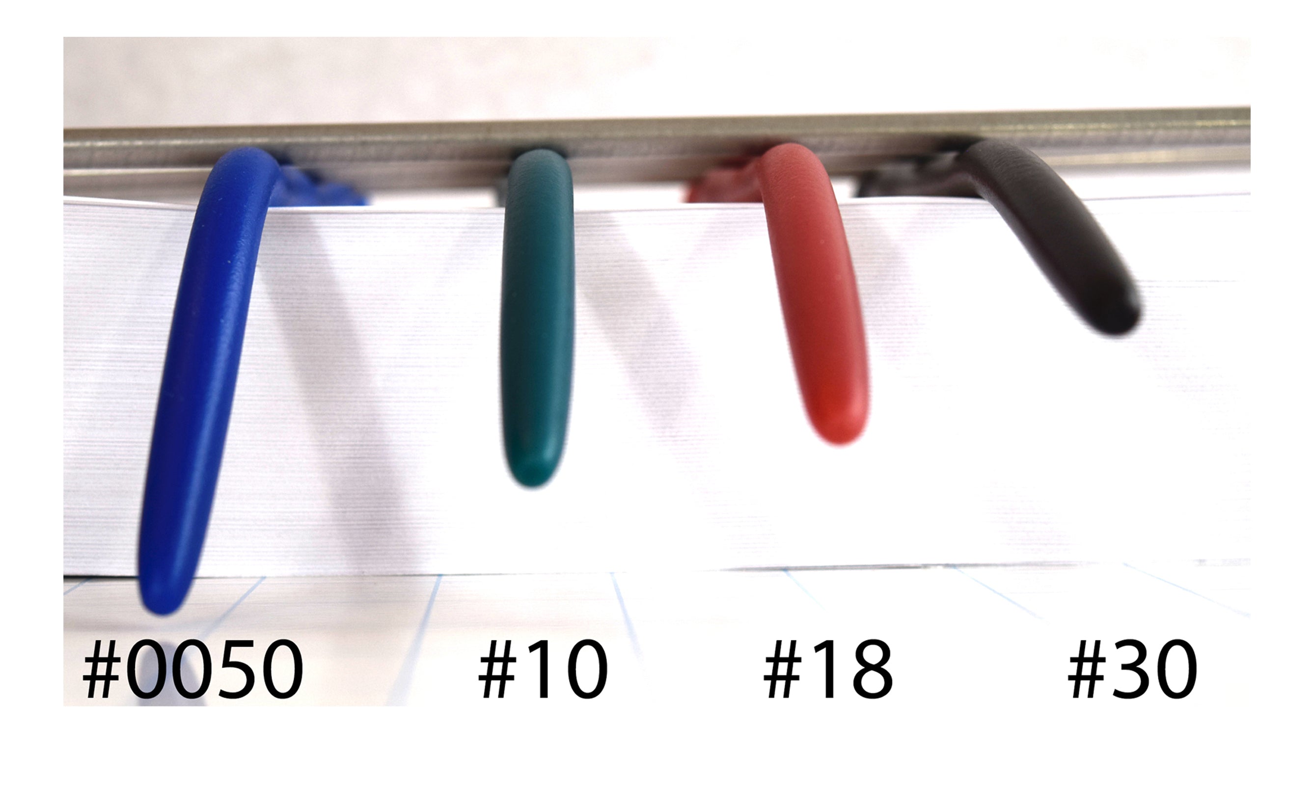 Front view comparison showing four silicone rods of varying firmness (#0050, #10, #18, #30) drooping from a clamp to illustrate flexibility, on a white background.