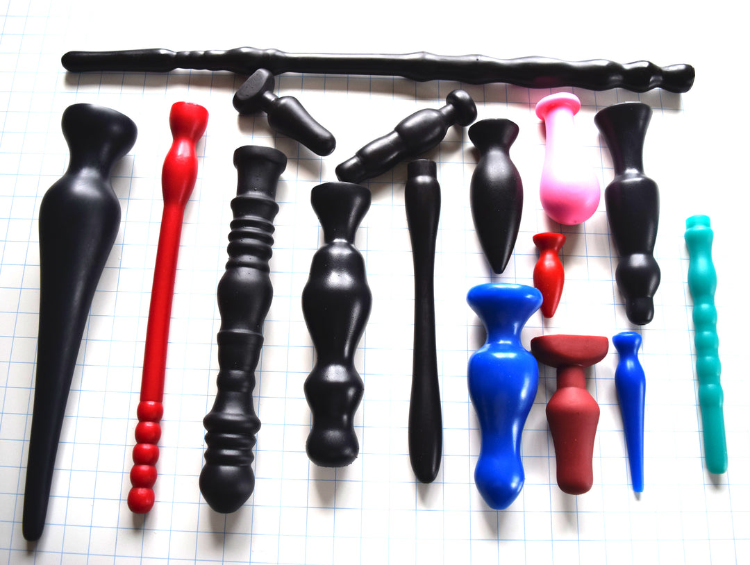 Assortment of custom-cast silicone nozzles and plugs in various colors, shapes, and sizes arranged on a grid work surface