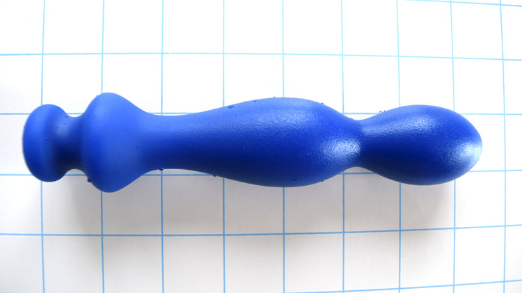 Small blue silicone ball tip nozzle, 1.25 inch diameter, with double bulb shape and safety flange on a grid background