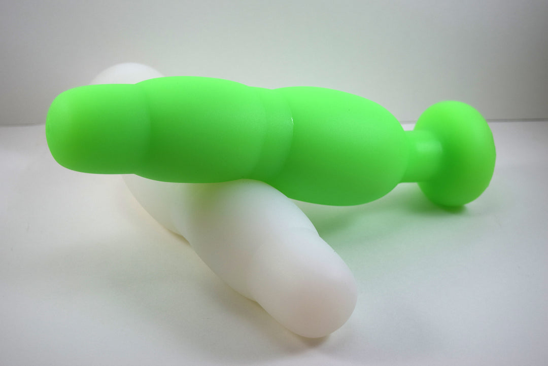 Fluorescent green and white silicone SNC MAX retention nozzles interlocked horizontally on a white background, displaying the 3-inch maximum expansion bulb and safety flange.