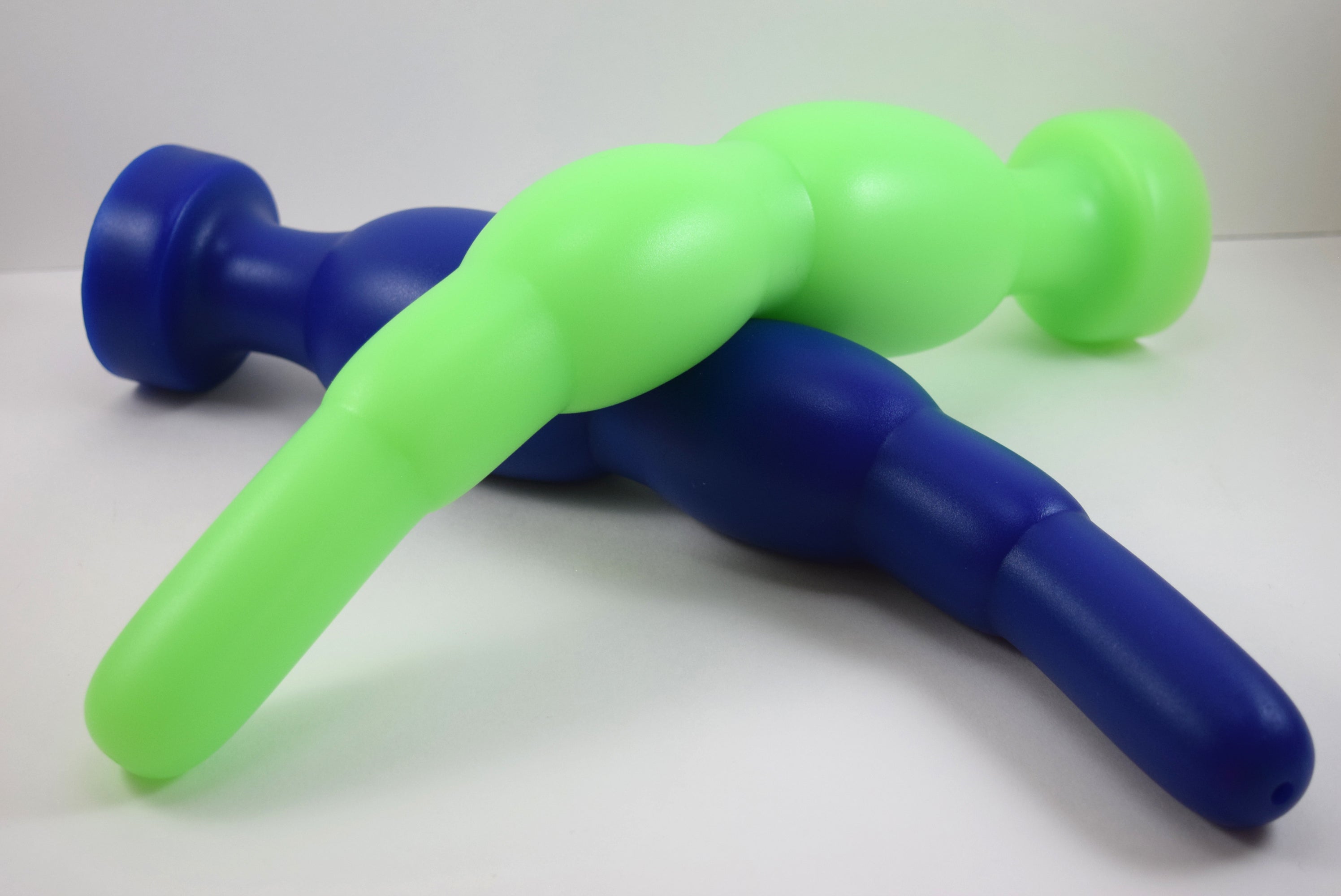 Blue and fluorescent green silicone SNC MAX EXT retention nozzles resting together on a white surface, showcasing the extended 1.5-inch tip profile, multi-bulb expansion zones, and 3-inch retention flanges.