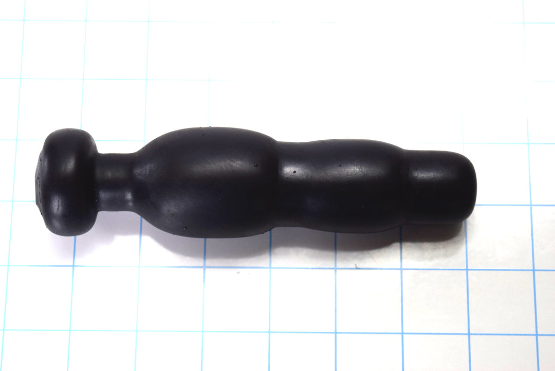 Black silicone SNC MINI retention nozzle with a compact triple-bulb design and safety flange resting on a blue grid background.