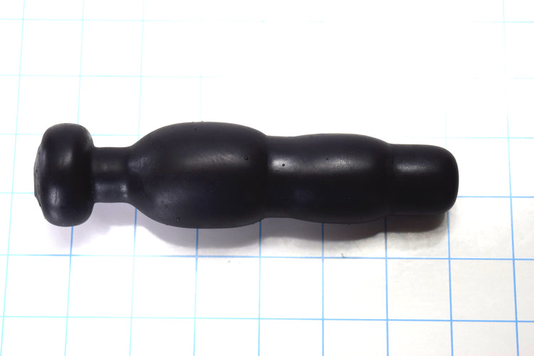 Black silicone SNC MINI retention nozzle with a compact triple-bulb design and safety flange resting on a blue grid background.