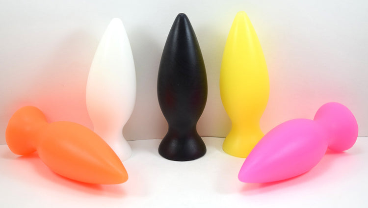 A group of five colorful stubby silicone retention plugs shown standing and lying down on a white surface.
