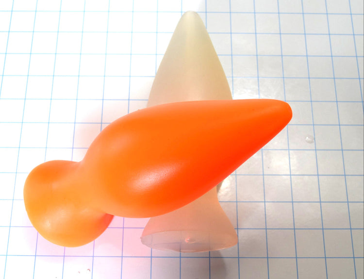 Orange and clear silicone retention plugs crossed over each other on a blue grid background.