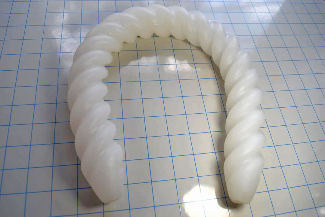 Spiral 22-inch double-ended silicone colon tube in translucent white on a blue grid background, displaying its continuous 1.6-inch diameter spiral helical ribs and identical tapered tips