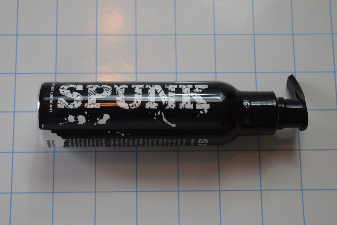 A 4oz black pump bottle of SPUNK Hybrid creamy white personal lubricant displayed on a blue grid background.