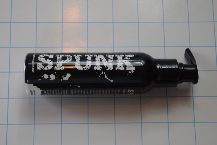 A 4oz black pump bottle of SPUNK Hybrid creamy white personal lubricant displayed on a blue grid background.