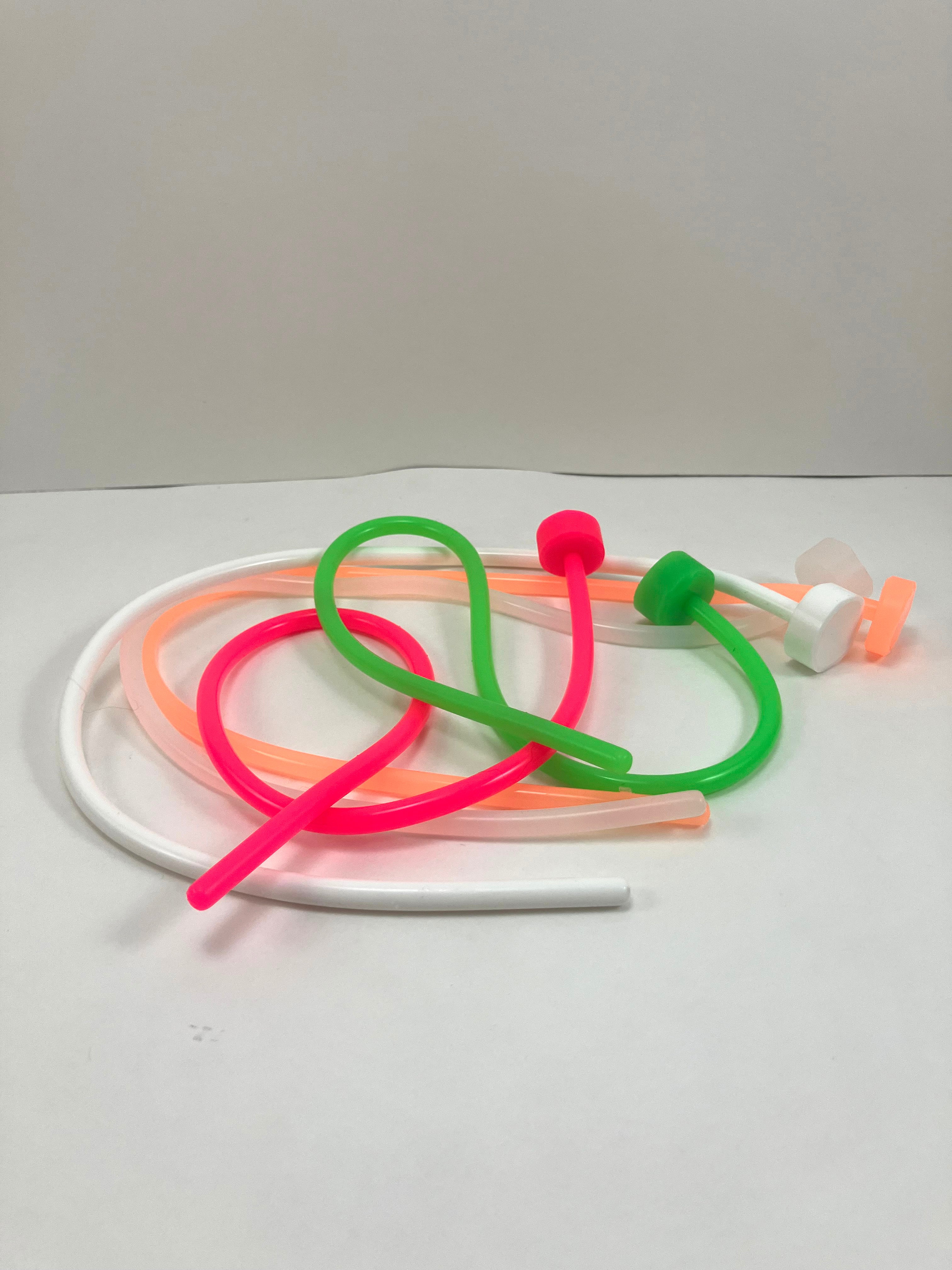 A collection of silicone sounds in various sizes and colors, including pink, green, orange, and white. They appear flexible and have a smooth surface.