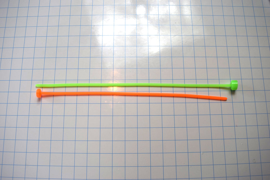 SSND-5.5mm silicone urethral sounds in fluorescent green and fluorescent orange featuring 5.5mm diameters (16 French), smooth rounded tips, solid core constructions, and 15-inch insertable lengths displayed side-by-side on a grid background.