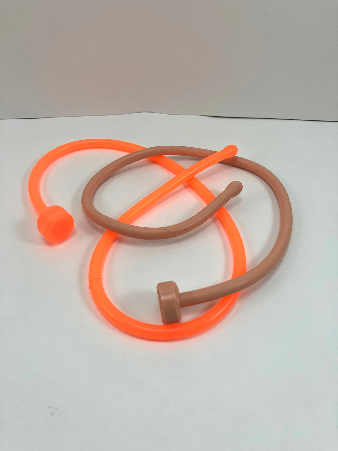 SSND-6.5BT silicone sounds shown as a pair in solid orange and translucent white mixed with standard color selections, featuring expanded ball tips, slim uniform shafts, and flat safety base flanges on a grid background.