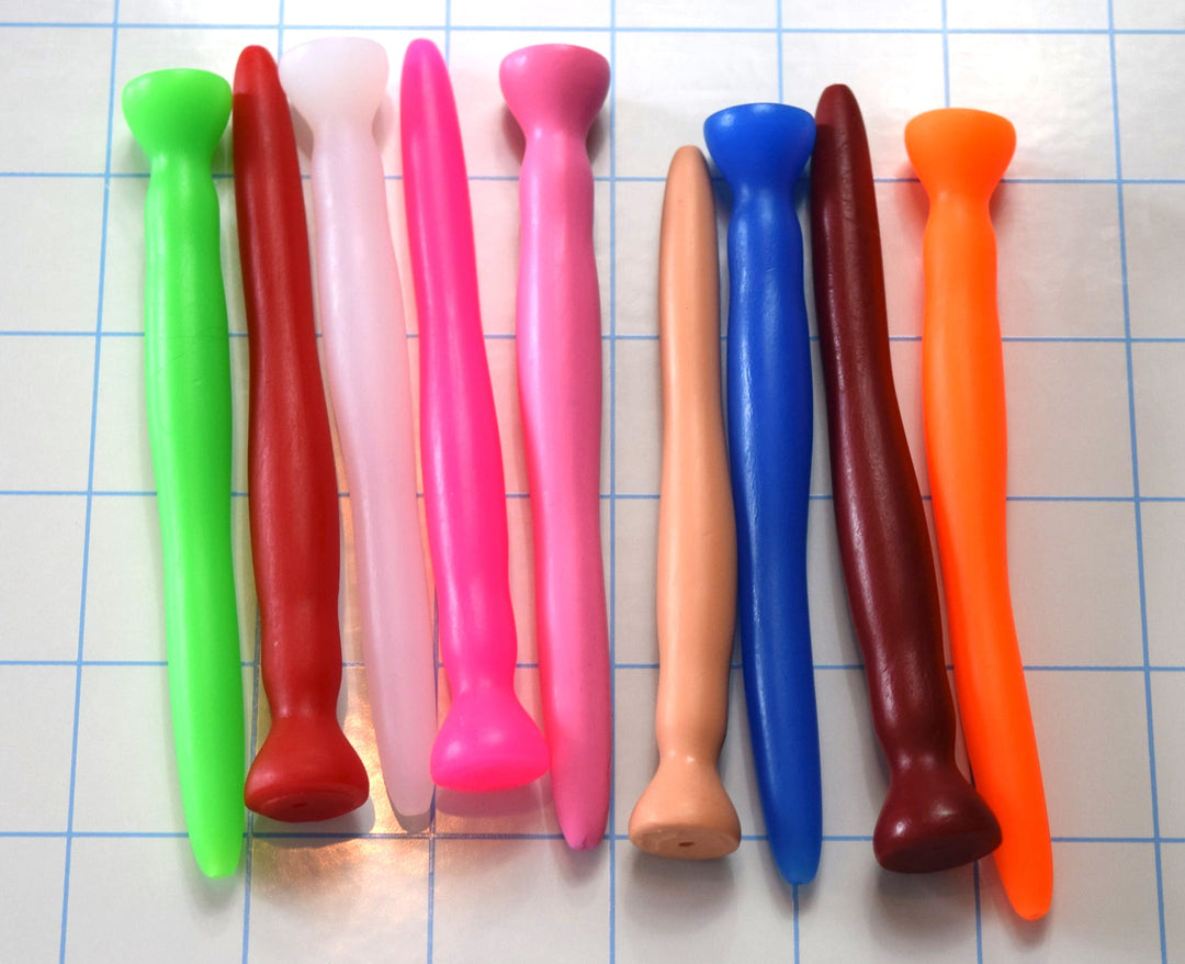 A row of colorful silicone urethral sounds in various colors lined up vertically on a blue grid background.