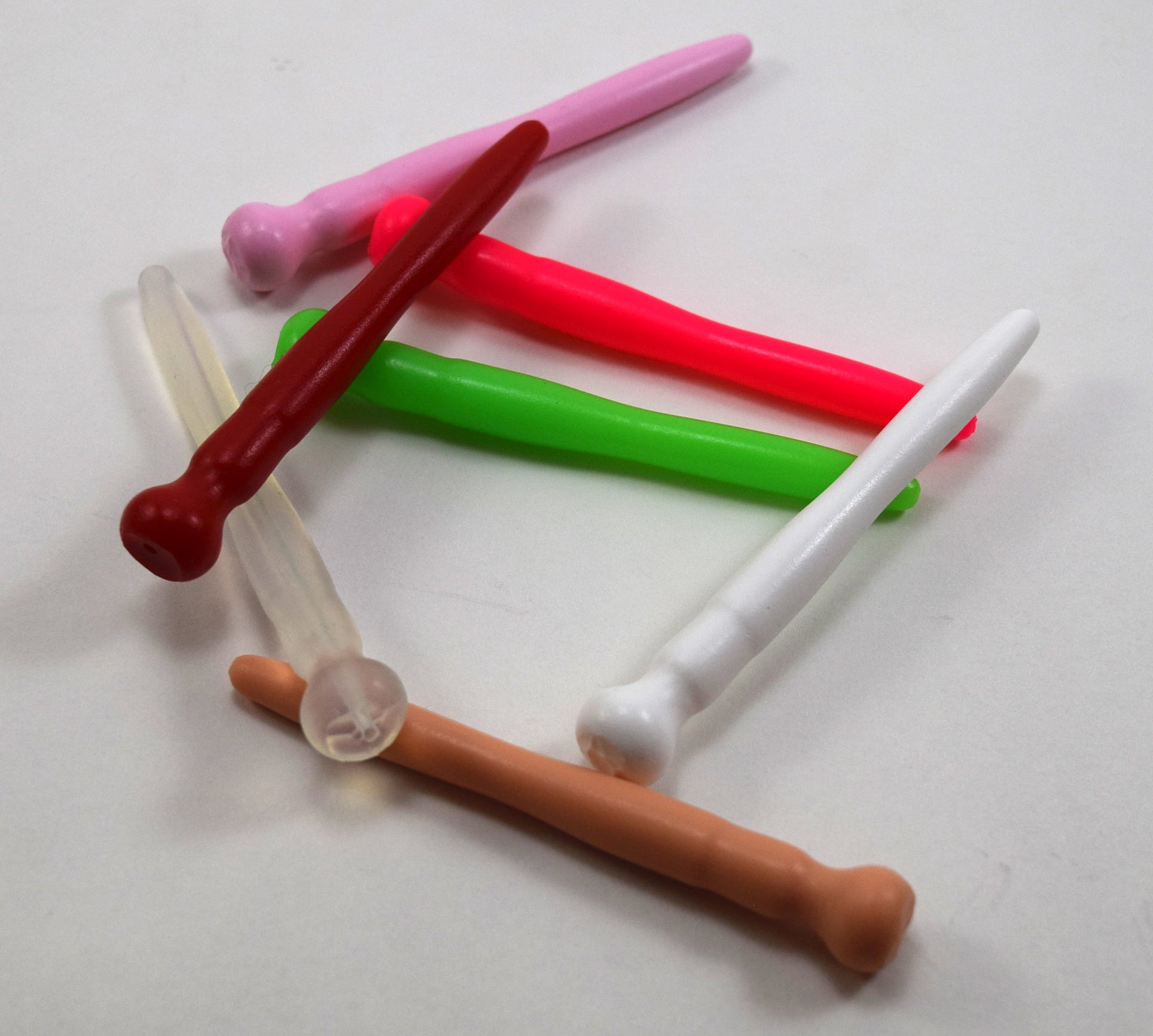 A stacked group of colorful silicone urethral sounds shown in assorted colors on a plain white surface.