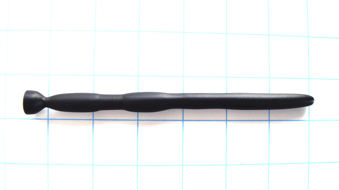 SSND-BMK2 flexible black silicone urethral sound shown horizontally on a grid background from Screenshot 2026-07-02 131647.png, highlighting its 8mm tapered tip, 9.5mm forward shaft, dual 11mm expansion barrels, 5.5mm hold-in-place retention groove, and flared safety base flange.