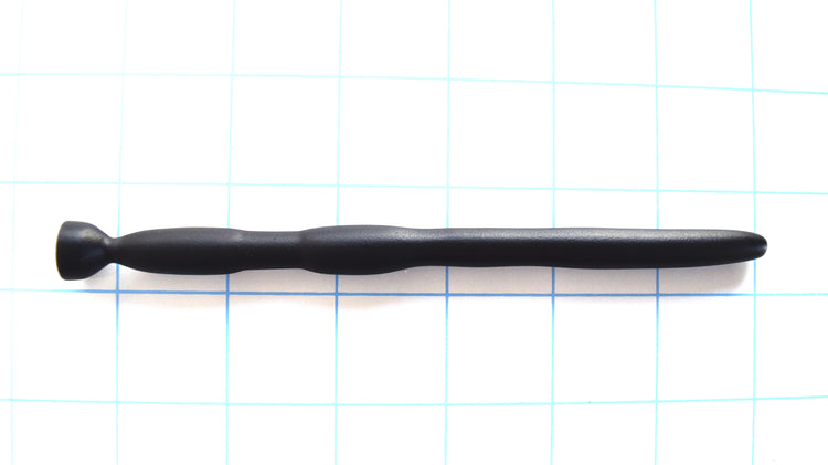 SSND-BMK2 flexible black silicone urethral sound shown horizontally on a grid background from Screenshot 2026-07-02 131647.png, highlighting its 8mm tapered tip, 9.5mm forward shaft, dual 11mm expansion barrels, 5.5mm hold-in-place retention groove, and flared safety base flange.