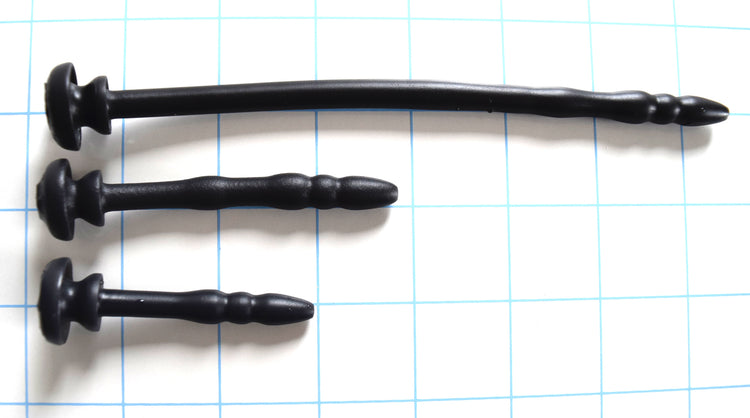 SSND-Chastity 8mm contoured black silicone urethral sounds shown in Short 2 inch, Original 2.75 inch, and Long 6.25 inch length variations horizontally on a grid background, highlighting the 5mm rounded tips, 8.8mm maximum ribs, and integrated retention base flanges.