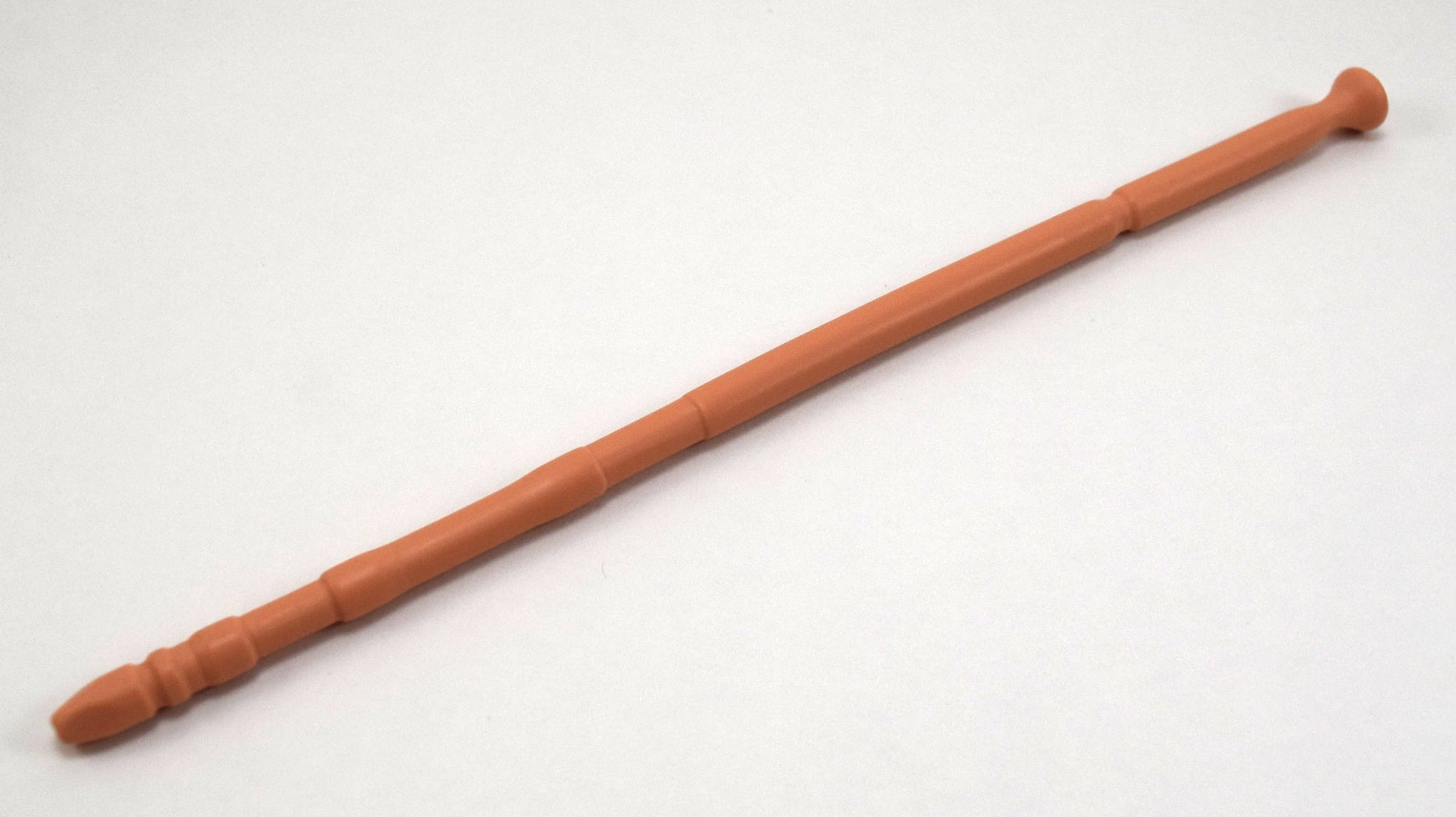A tan flesh-tone 13-inch contoured silicone sound with a multi-faceted tip lying diagonally on a white background.
