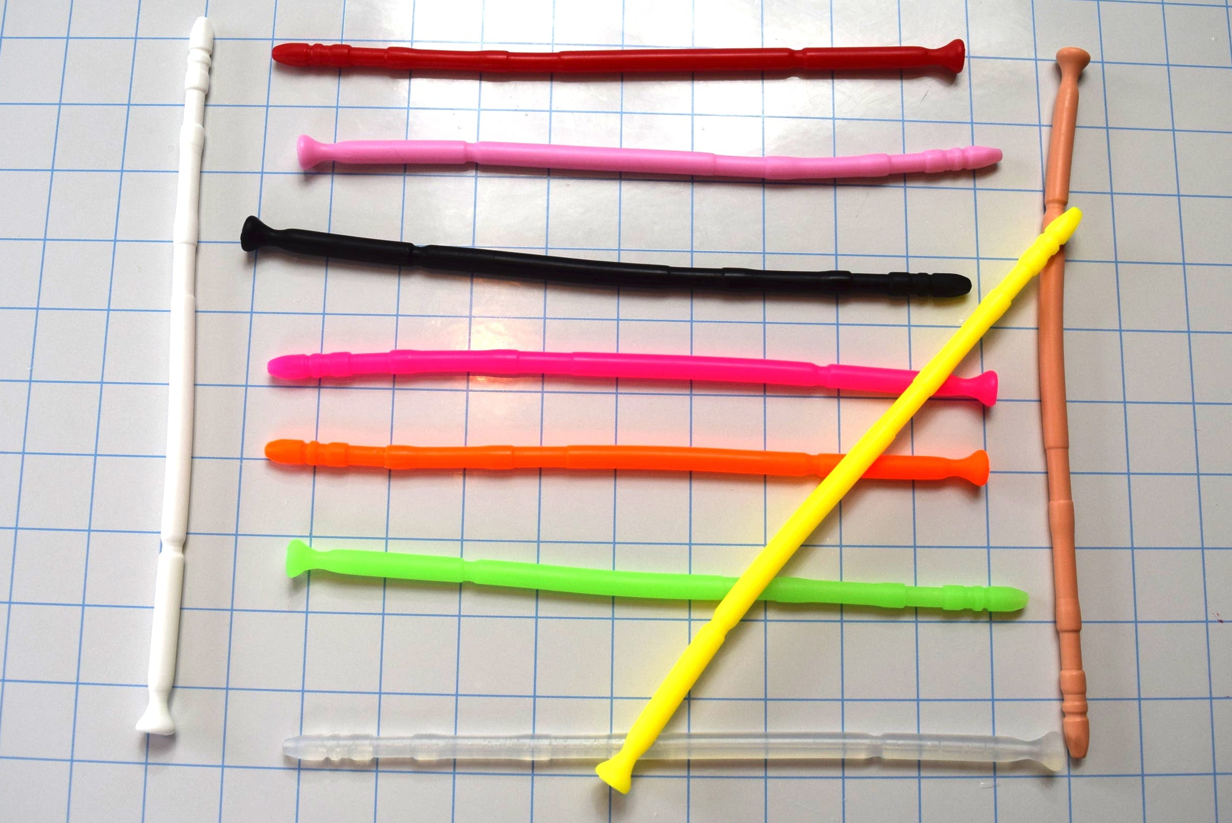 Multiple colorful 13-inch contoured silicone sounds laid out neatly across a blue grid cutting mat.