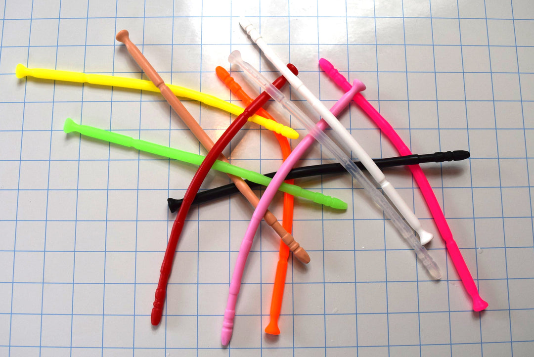 A scattered pile of colorful 13-inch contoured silicone sounds with multi-faceted tips on a blue grid background.