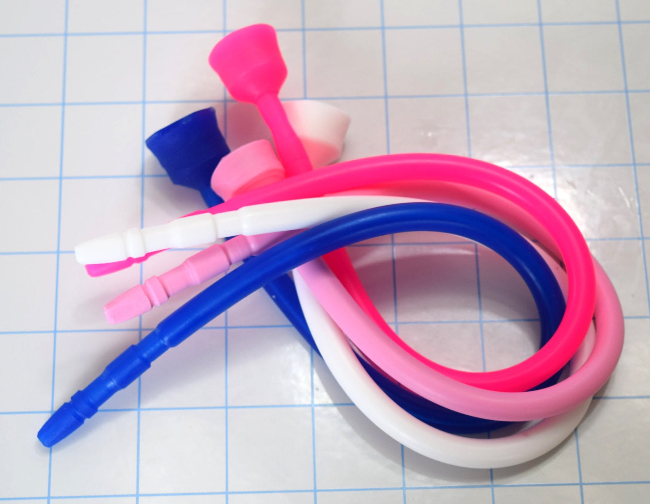 A coiled pile of multi-colored 13-inch contoured silicone sounds resting on a blue grid mat.