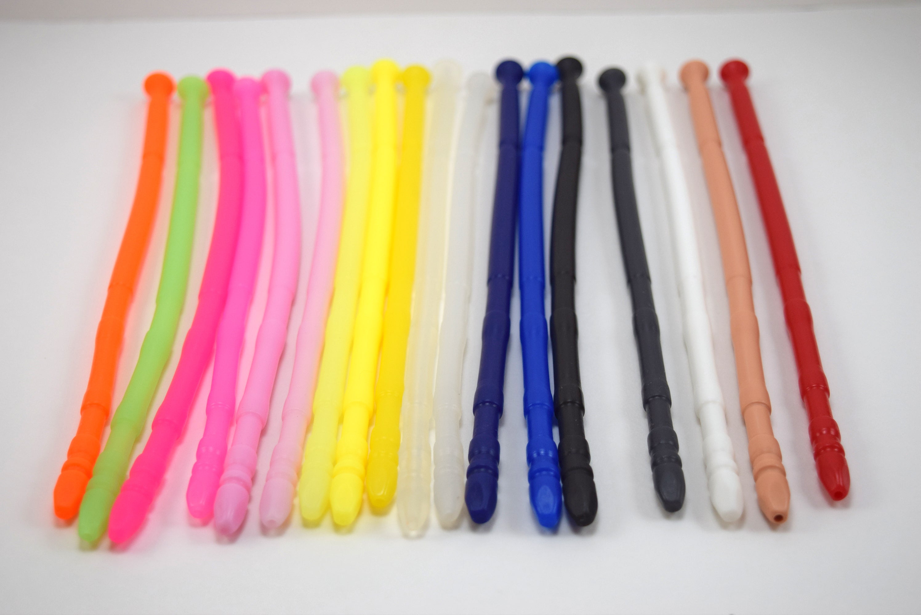 A row of colorful 8mm contoured silicone urethral sounds with multi-faceted tips displayed on a plain white surface.