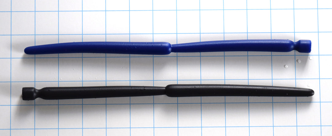 SSND-Double Expansion 12-inch advanced silicone urethral sound resting on a blue grid background, showcasing its dual 14mm and 13.7mm expansion nodes, 9mm tapered tip, and flared safety base.