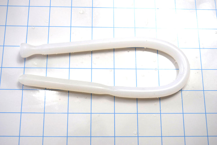 Translucent white SSND-DS 9-12 flexible silicone sound bent in a U-shape on a blue grid mat, displaying its grooved tip and flanged safety base.