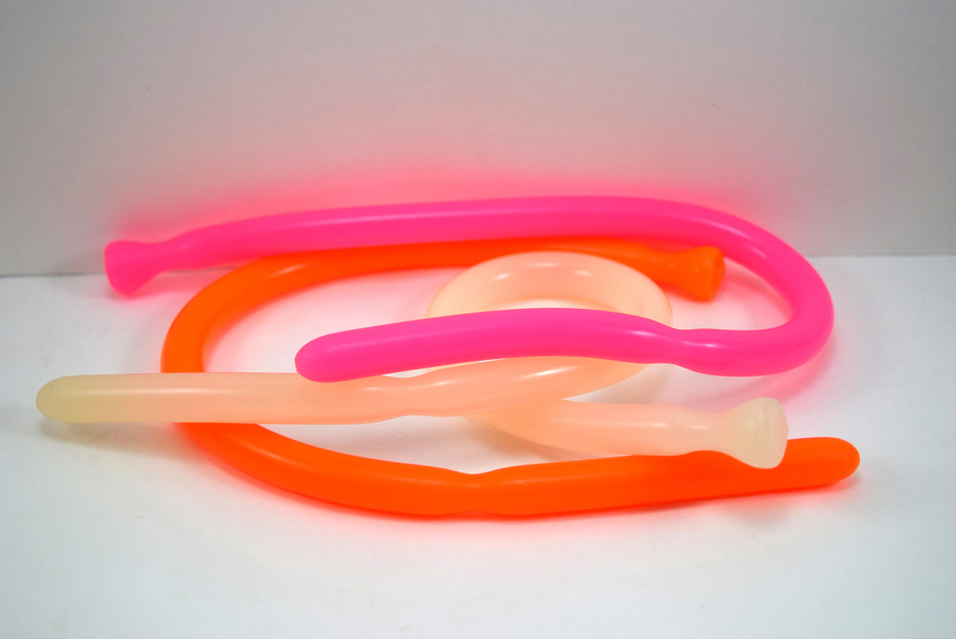 SSND-DS 9-12 flexible silicone sounds coiled together on a white background, pictured in bright pink, neon orange, and translucent clear.