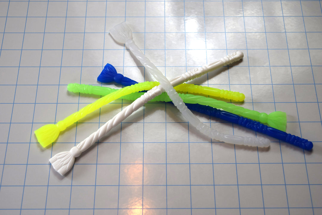 SSND-FLORENTINE10 silicone urethral sounds in various colors including translucent white, blue, green, and yellow featuring elliptical rounded tips, alternating florettes, barrel sections, ribs, twisted rope textures, retaining balls, flat safety flanges, and 9.25-inch insertable lengths displayed together on a grid background.