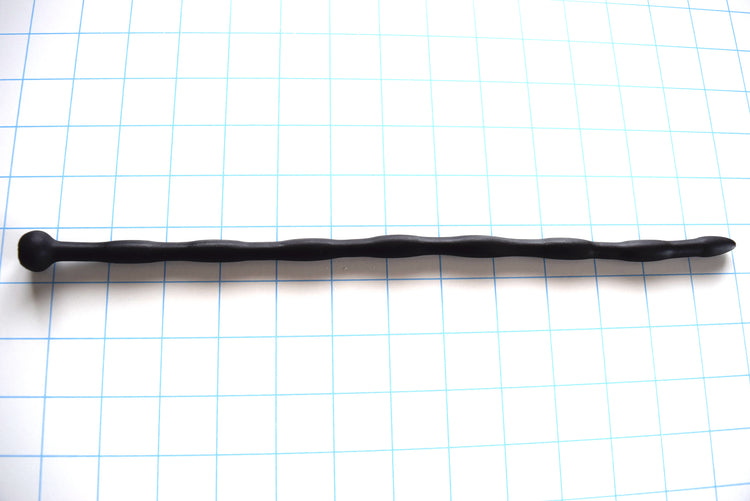 SSND-JAS4 13-inch flexible black silicone urethral sound shown horizontally on a grid background from Screenshot 2026-07-02 125743.jpg, highlighting its 10mm egg-shaped entry tip, seven repeating 10mm sensory swells, 8mm sloped valleys, and a prominent 16mm ball safety flange.