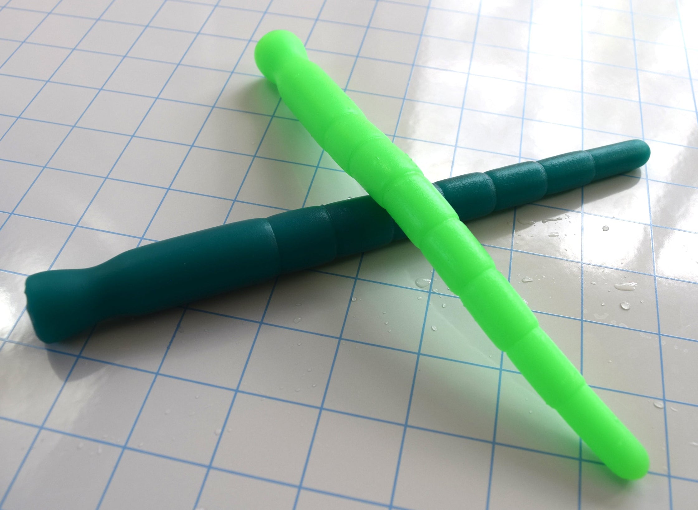 A neon green silicone stretching sound crossed over a dark teal silicone sound on a blue grid surface.