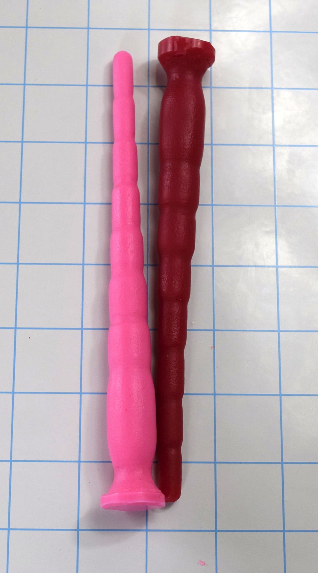 Pink and dark red 8-stage segmented silicone sound probes laid side-by-side on a grid mat.