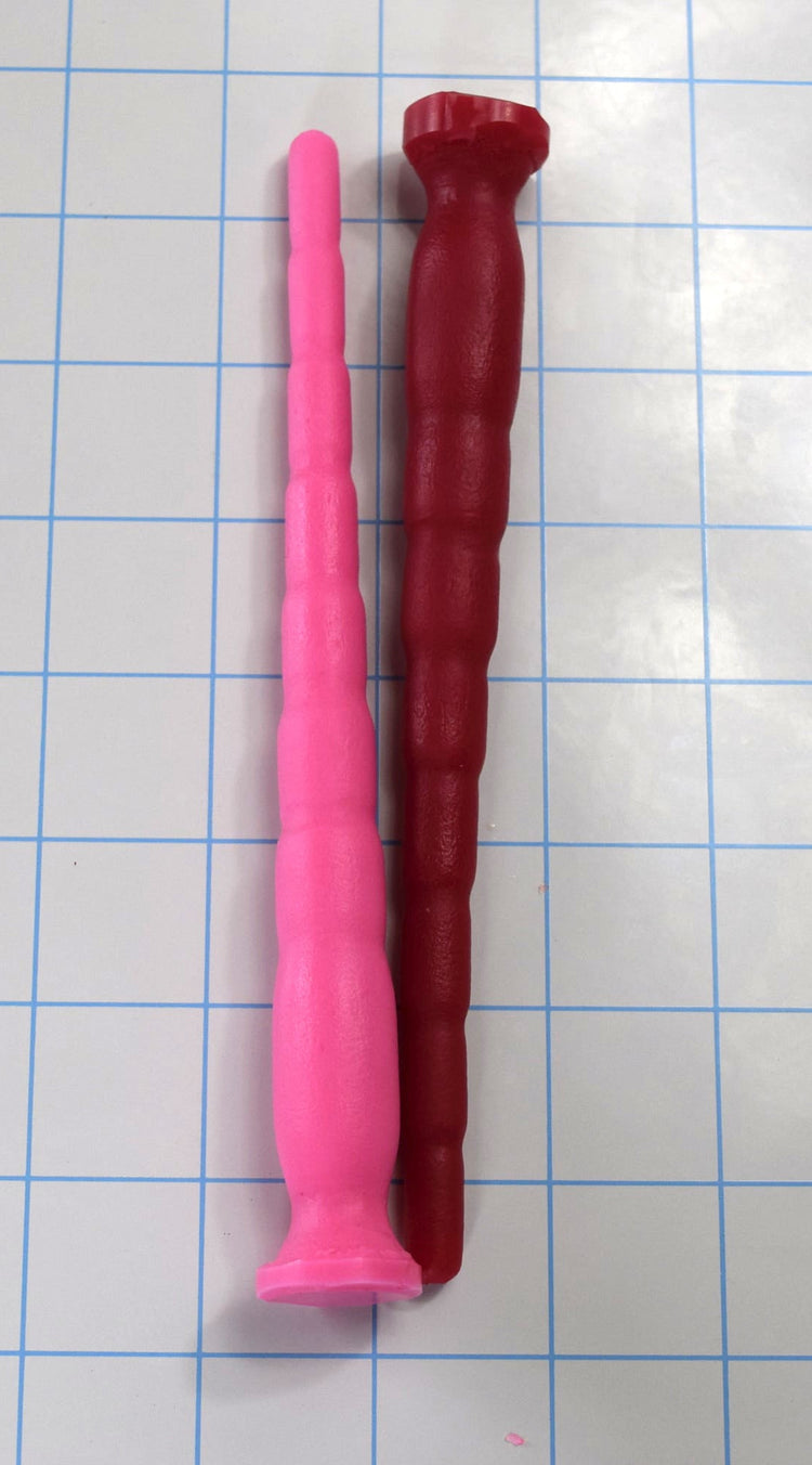 Pink and dark red 8-stage segmented silicone sound probes laid side-by-side on a grid mat.