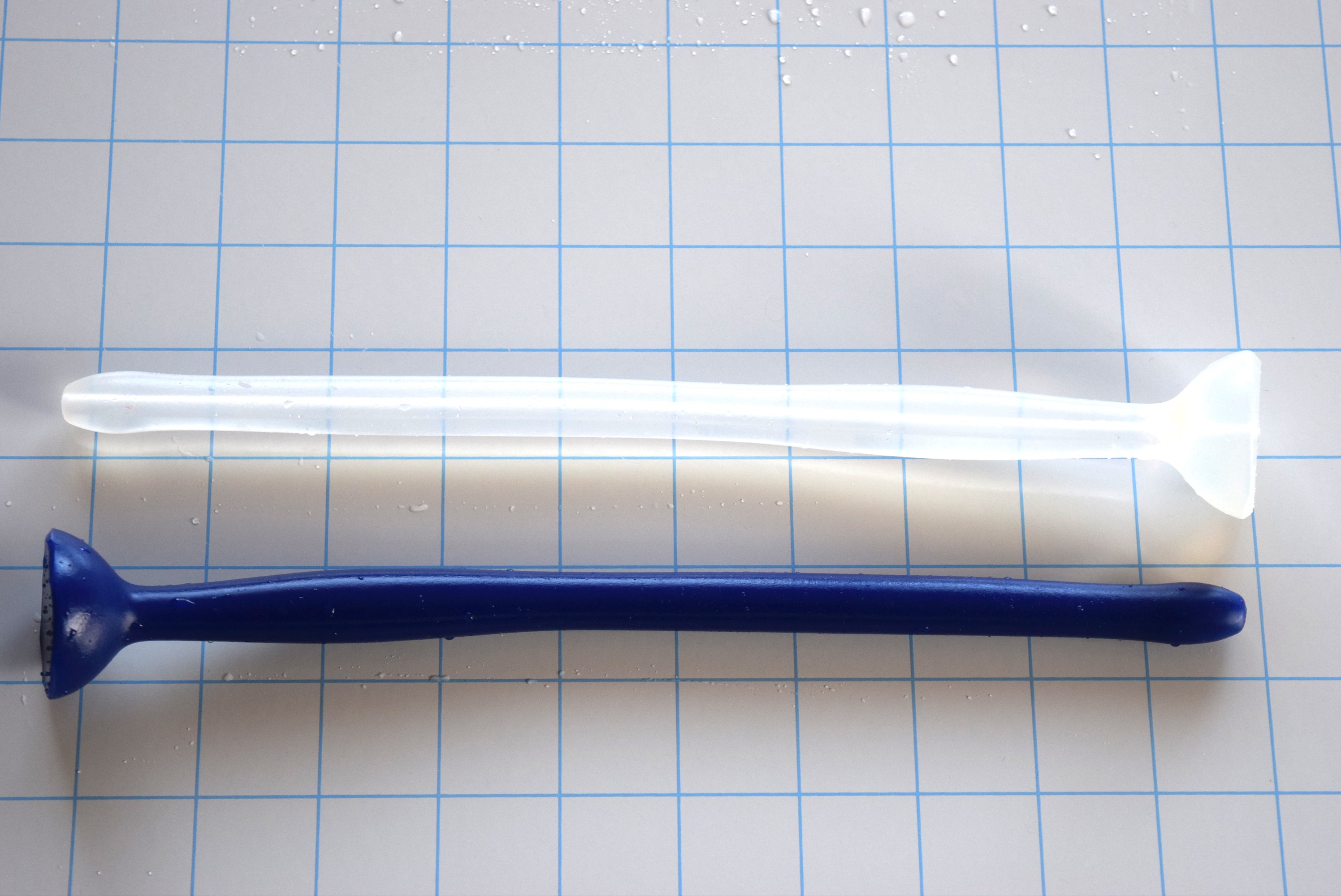 Dark blue and translucent white SSND-MGCWAND10 silicone sounds, 10 inches long, featuring a 13.5mm tip, 15.8mm oval expansion node, 11.5mm retention valley, and extra-large safety flange on a blue grid background.