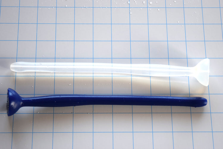 Dark blue and translucent white SSND-MGCWAND10 silicone sounds, 10 inches long, featuring a 13.5mm tip, 15.8mm oval expansion node, 11.5mm retention valley, and extra-large safety flange on a blue grid background.