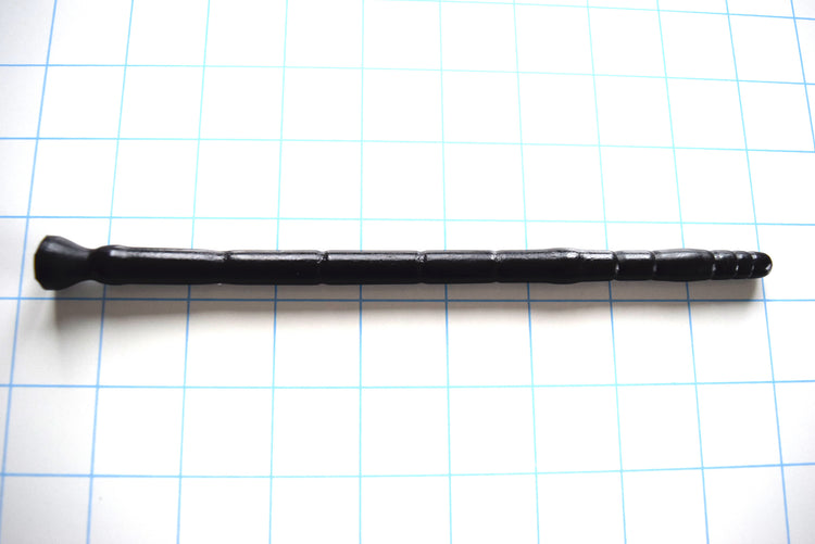 SSND-MLTIDML 8-12 intermediate black silicone urethral sound shown horizontally on a white background with 1"x1" blue grid squares from Screenshot 2026-07-02 160647.jpg, highlighting its graduated micro-segments near the 7mm tip, 12mm peak stretch barrel, and 8-inch insertable length.