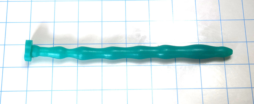 Teal green multi-ribbed silicone sound probe with varied segments and a flanged base on a grid surface.
