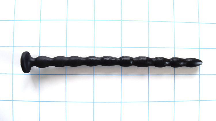 SSND-MRB 8-10mm flexible multi-ribbed silicone urethral sound, featuring a gently tapered tip, 10 graduated ribs (8.4mm to 10mm), a 6.7mm retention valley, a flared base flange, and 6-inch insertable length, shown on a grid background.