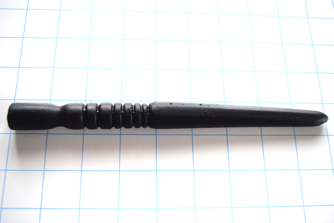 SSND-OCTA-SIDE expert black silicone urethral sound shown horizontally on a white background with 1"x1" blue grid squares from Screenshot 2026-07-02 154901.jpg, highlighting its 120mm octagonal faceted shaft peaking at 18mm, 45mm fast ribbed section, and 18.5mm multi-tier retention base.