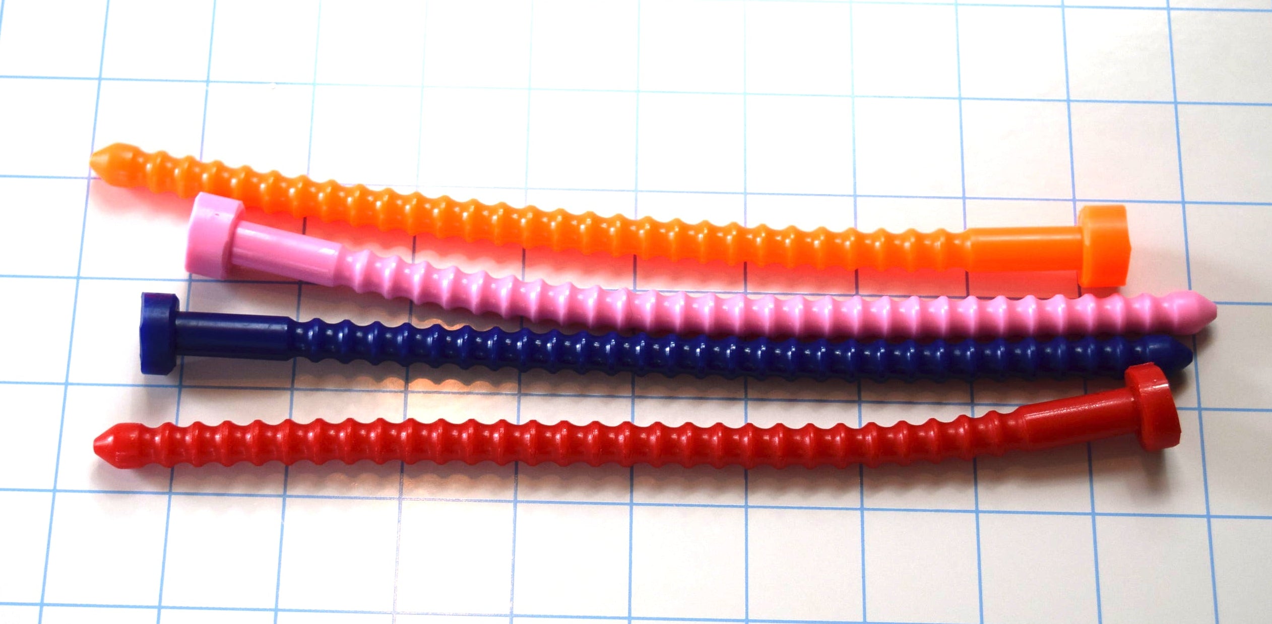 Orange, pink, blue, and red 6mm ribbed silicone sound probes laid horizontally in a vertical stack on a grid.