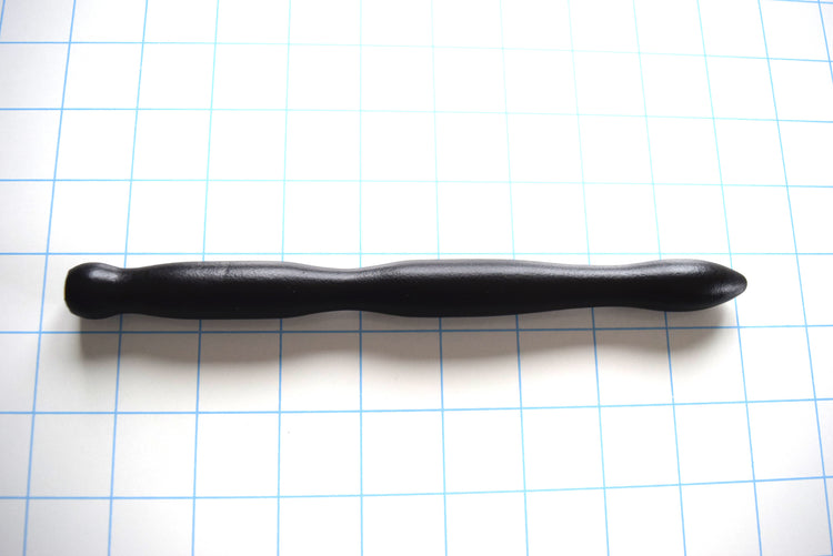 SSND-RIPPLE 6-18 large black silicone urethral sound shown horizontally on a white background with 1"x1" blue grid squares from Screenshot 2026-07-02 154307.jpg, showcasing its three massive expanding wave ripples peaking at 18mm, 8-inch insertable length, and thick safety flared base.