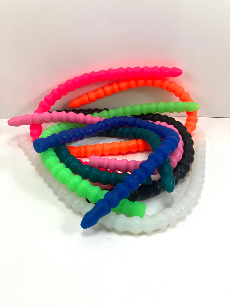 A collection of SSND-RNDMRIB silicone urethral sounds in various colors including pink, orange, green, blue, black, and translucent white, featuring alternating ribbed sections and safety flange bases on a white background.