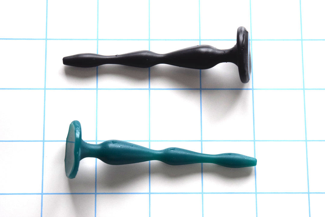 SSND-SHRTCATH 7-12 short cascading silicone urethral sound shown in both black and green options on a blue grid background, highlighting the 7.1mm, 8.6mm, and 12mm expansion peaks, deep narrow valleys, and a flat 27mm safety base flange.