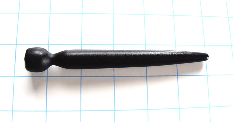 Black tapered silicone urethral sound lying horizontally on a blue grid background.