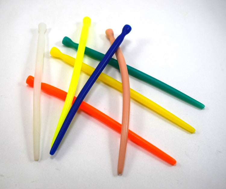 A scattered pile of smooth, colorful silicone urethral sounds on a white surface.