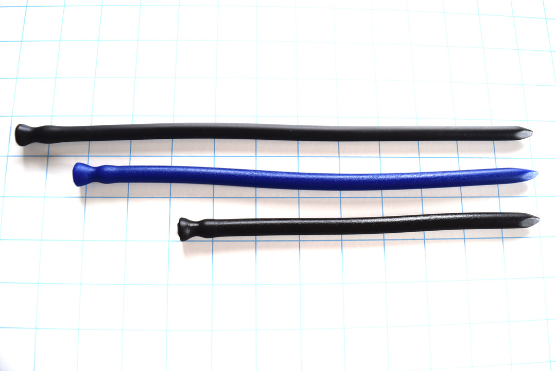 Black and blue spike-tip silicone urethral sounds in three lengths resting horizontally on a blue grid background.