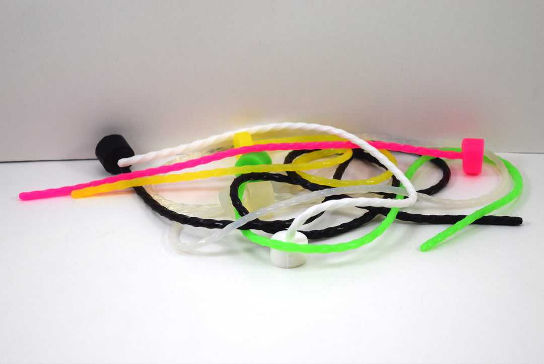 A loose heap of thin, colorful spiral-twisted silicone urethral sounds on a plain white surface.