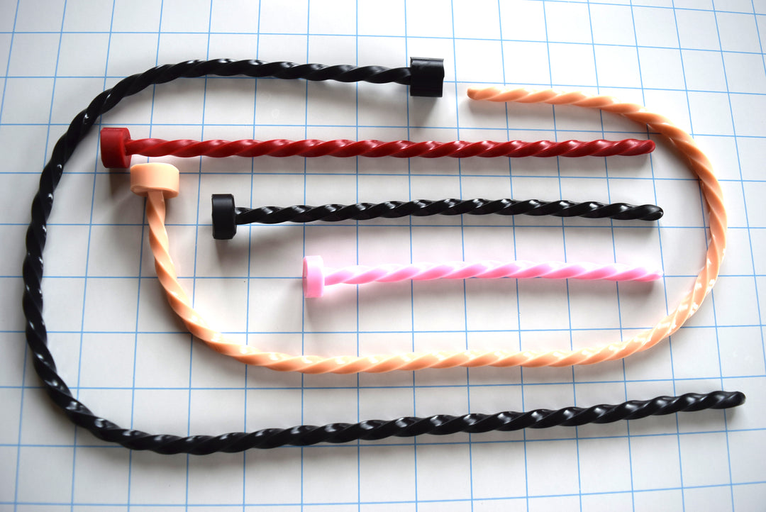 Spiral-twisted silicone urethral sounds shown in various lengths and colors on a blue grid background.